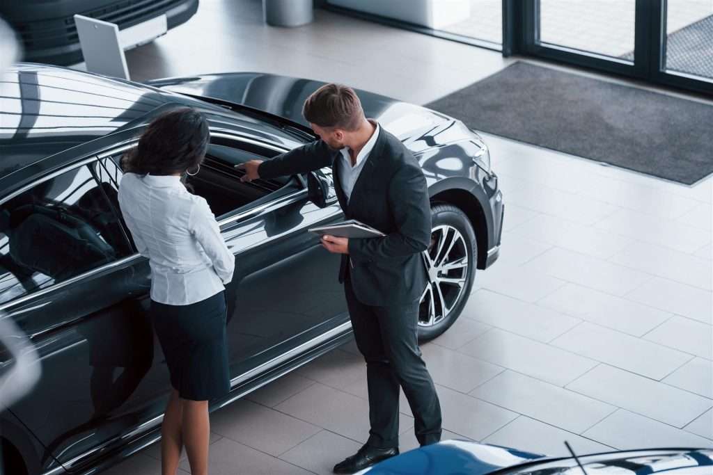 Salesperson showing a car to a customer at Staten Island car dealerships.