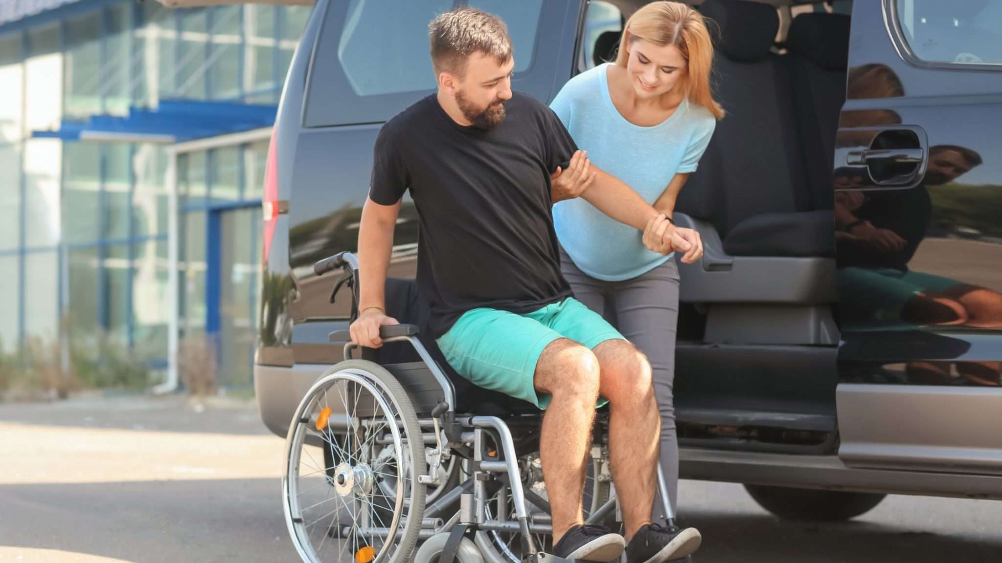 A wheelchair user being assisted from a van at Staten Island car dealerships.